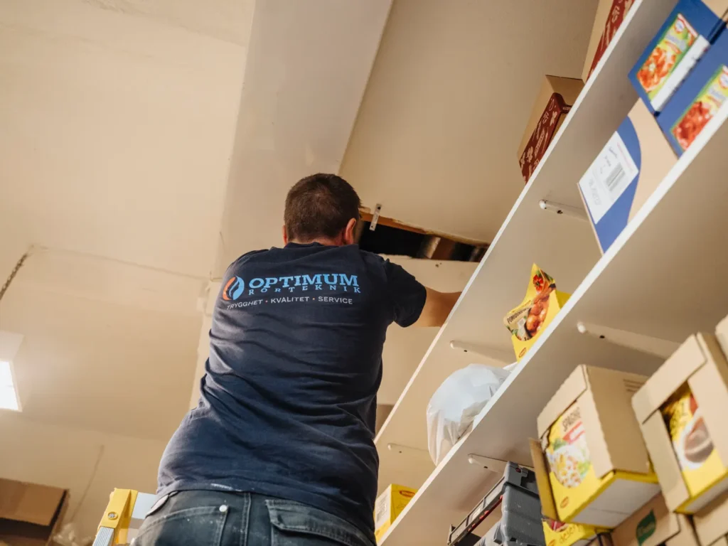 Stavros från Optimum Rörteknik arbetar vid en taklucka i en lokal